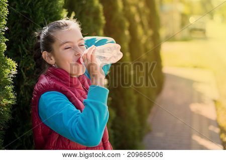 Beautiful girl drinking water after jogging in outdoor. A beautiful girl is drinking water the hot sun in the park. Healthily concept. Healthy lifestyle concept. copy space. Portrait beautiful girl