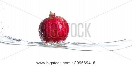Red, whole and ripe garnet on the turbulent water. Water splashes. Isolated picture on white background