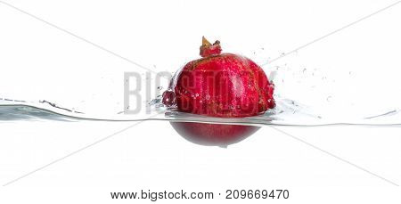 Red, whole and ripe garnet break water surface. Water splashes. Isolated picture on white background