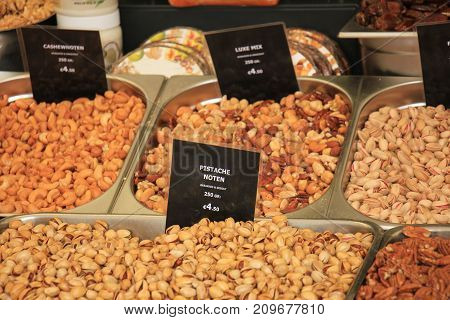 Fresh nuts on a market stall (text on tags: names and prices of various nuts in Dutch pistacho nuts and a mixture of peanuts and cashew)