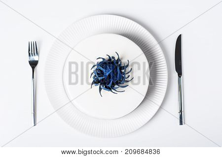 Top view of wedding modern trendy white cake on plate isolated background with dinnerware set decorated blue trendy chocolate flower. Dessert Sweet Food concepts. Mousse cake with white glaze Flat lay