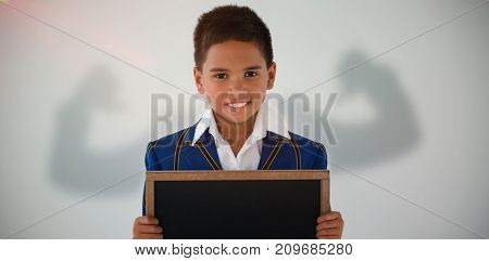 Silhouette of man flexing muscels against schoolboy holding blank writing slate against white background