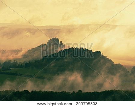 Distant Mountain Range And Heavy Clouds Of Colorful  Mist Above Deep Valleys