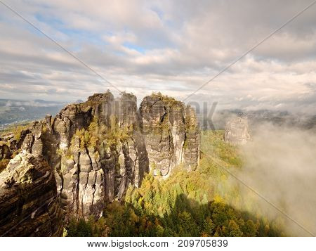 Distant Mountain Range And Heavy Clouds Of Colorful  Mist Above Deep Valleys