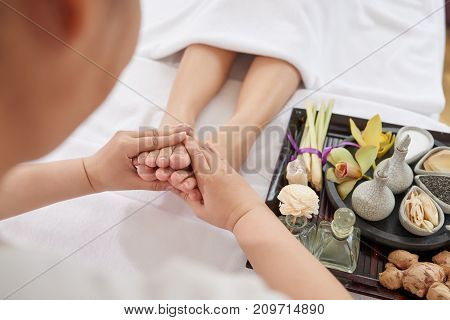 Woman receiving deep foot massage in spa salon