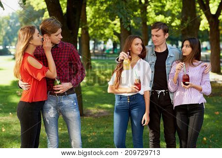 Jealousy and envy in friends relationship. Cheerful young people with detox cocktail having outdoor summer party