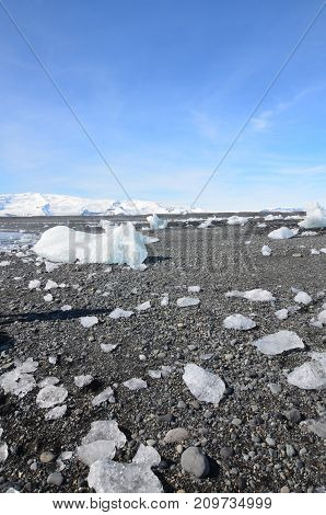 Blue skies with chunks of glaciers on a black sanded beach