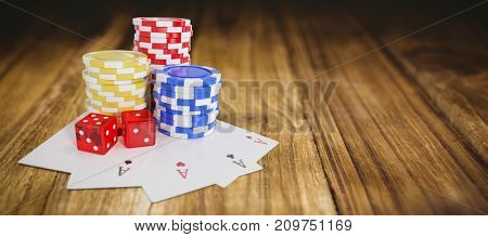 Tilt image of casino tokens with playing cards and dice against wooden table
