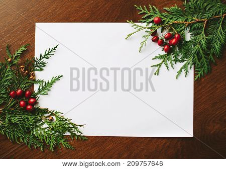 Merry Christmas greeting card with Chrirstmas decor fir twigs on a wooden background.