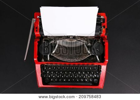 Photo of vintage red typewriter on the table with paper onblack background