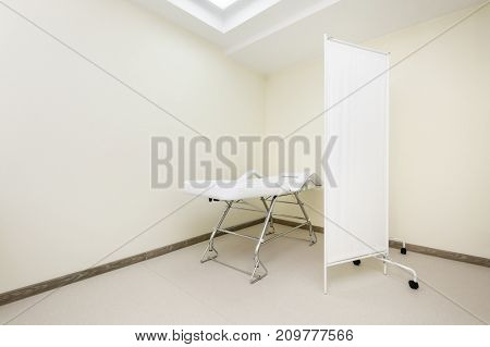 Clean designed and brightly lit massage room with empty table