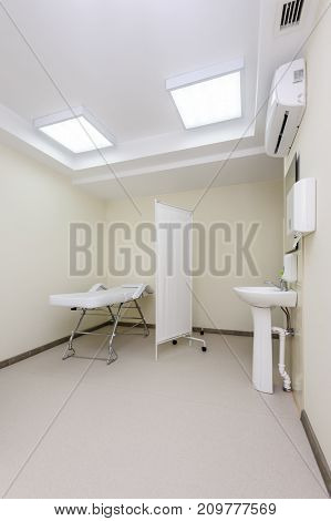 Clean designed and brightly lit massage room with empty table