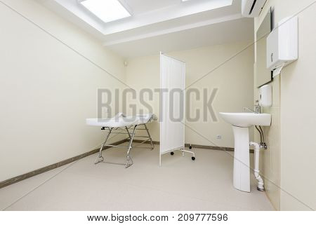 Clean designed and brightly lit massage room with empty table