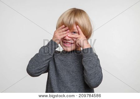 Emotional portrait of caucasian boy. Handsome happy child, photo on grey background