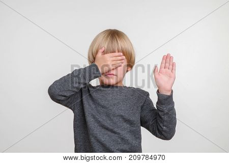 Emotional cute portrait of caucasian boy. Handsome happy child, photo on grey background