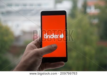 London, United Kingdom, october 3, 2017: Man holding smartphone with Tinder logo with the finger on the screen