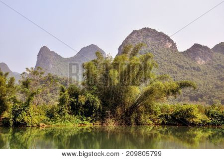Yulong river with luxuriant bank vegetation in the picturesque scenery of Yangshuo county in Guangxi province in China.