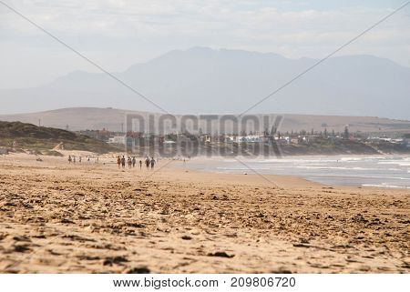 A group of people walking along a beach in Mossel Bay South Africa