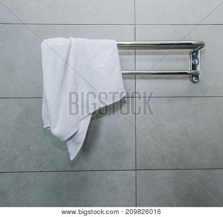 Stainless steel towel on grey cement wall with brown towel in bathroom