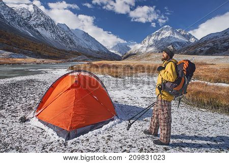 Hiker with backpack at camping in the mountains during springtime. Backpacker with bierd looking at the top.