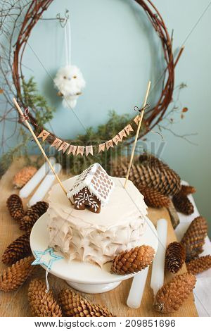 New Year or Christmas chocolate cake with cream decorated with a gingerbread house and a congratulatory inscription in Russian. Selective focus.