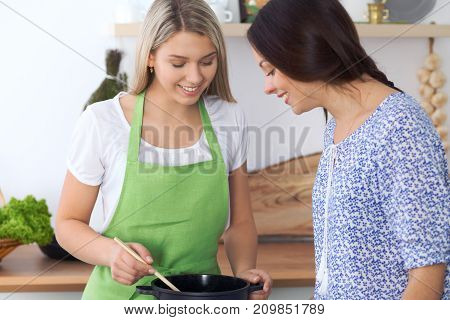 Two young happy woman making cooking in the kitchen. Friendship and culinary concept.