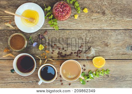 Tea, coffee, cocoa in cups, chicory, lemon, mint, jam made of rose petals, dried lime, honey on the old wooden background. Toned image. Top view.