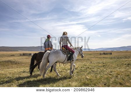 Couple Riding Horses In A Landscape Of Northern Mongolia
