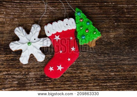 gingerbread christmas iced snowflake, stocking and evergreen tree cookies on aged wooden textured background