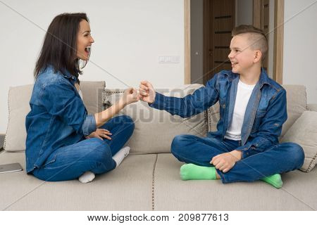 Happy mother and son sitting on sofa and using digital tablet at home