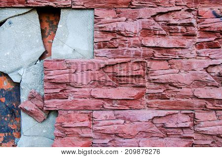 The broken dark red color tile on the tiled wall of the building requires repair