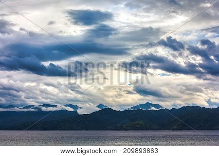 Forest on the mountain slopes of the island beautiful clouds above it view from the Bali sea space for text. Gili Trawangan island, Lombok, Indonesia.