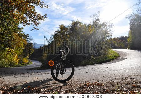 Bicycle on road on bend under a mountain. Cycle on the road on sunny autumn day
