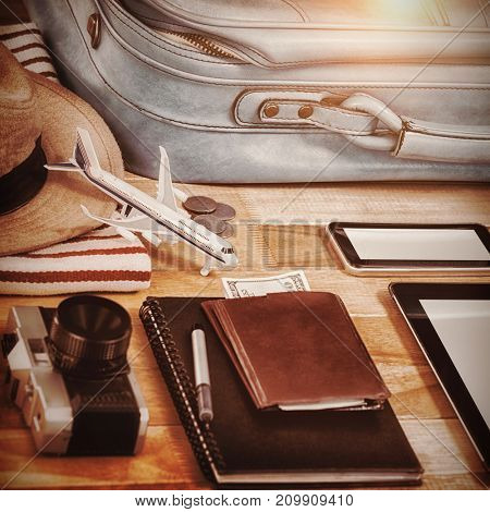 High anlge view of diary with currency by digital tablet and luggage on table