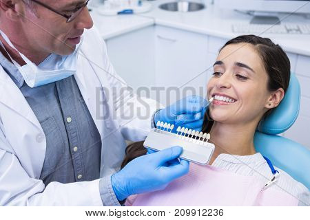 High angle view of dentist holding equipment while examining woman at clinic