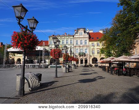 BIELSKO-BIALA POLAND EUROPE on AUGUST 2017: Main square in historical city center with colorful old buildings street lamps and red flowers clear blue sky in warm sunny summer morning day.