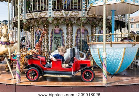 HONFLEUR, FRANCE - AUGUST 24, 2017: Caroussel at the harbor of Honfleur with a lovely little girl in a red car