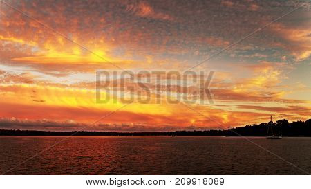 A striking inspirational golden sunset photo over tranquil lake water with colorful reflections at dusk. Captured on Lake Macquarie New South Wales Australia