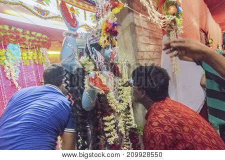 KOLKATA INDIA - JUNE 17 2017 - Hindu devotees worshipping Goddess Kali at night during Kali Puja Hindu festival of Deepavali or Diwali. Celebtated all over India. Shot under mixed light.