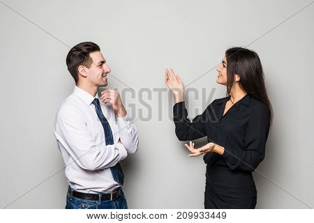 Smiling Businesswoman And Businessman Are Conversing Against Grey Background.