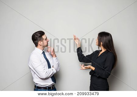 Smiling Businesswoman And Businessman Are Conversing Against Grey Background.