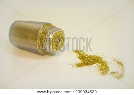 Sequins of gold color scattered on a white background and a black brush for their application