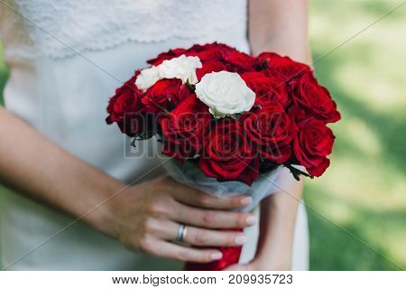 Young beautiful bride holds a bouquet hands
