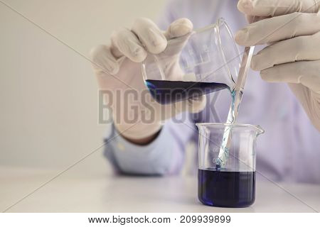 Scientist or medical in lab coat working in biotechnological laboratory equipment for research with mixing reagents in glass flask in clinical laboratory.