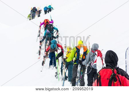 Group of cross-country skiers ascending a steep slope. Line of people in winter fairytale.