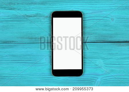 Mobile phone with blank screen mock up isolated on blue wood table background. Smartphone on wood table. Smartfone white
