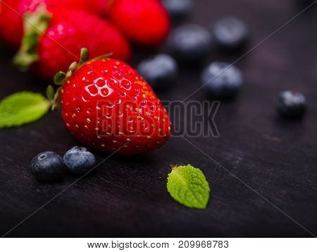 Fresh ripe fruits on a dark wooden table. Sweety red strawberries summer fruits on a dark brown background. Close-up of strawberry. Food concept.