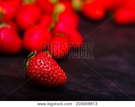 Fresh ripe fruits on a dark wooden table. Sweety red strawberries summer fruits on a dark brown background. Close-up of strawberry. Food concept.