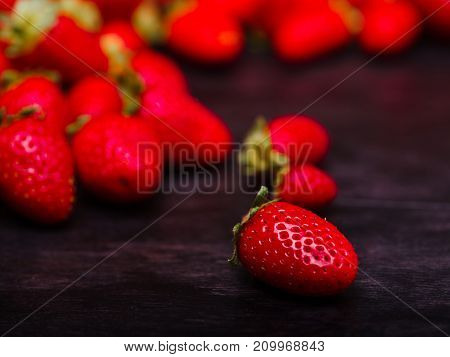 Fresh ripe fruits on a dark wooden table. Sweety red strawberries summer fruits on a dark brown background. Close-up of strawberry. Food concept.