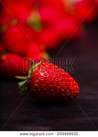 Fresh ripe fruits on a dark wooden table. Sweety red strawberries summer fruits on a dark brown background. Close-up of strawberry. Food concept.